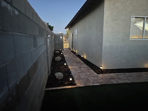 A narrow pathway flanked by a concrete wall and a building with a window.