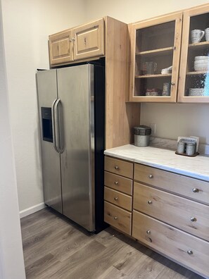Kitchen area with a refrigerator, cabinet, and drawers.