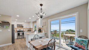 A modern kitchen with a central island, stainless steel appliances, and a chandelier. - Easy Beach Access, Spacious Decks & Striking Ocean Views - Harris Beach Overlook (Brookings)