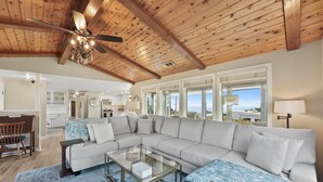 A spacious living room with a large sectional sofa, a glass coffee table, and a wooden ceiling with exposed beams. - Easy Beach Access, Spacious Decks & Striking Ocean Views - Harris Beach Overlook (Brookings)