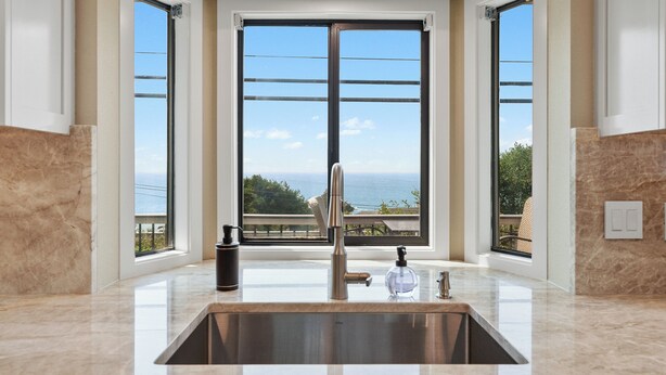 A modern kitchen with a large window, a stainless steel sink, and a view of the ocean. - Easy Beach Access, Spacious Decks & Striking Ocean Views - Harris Beach Overlook (Brookings)