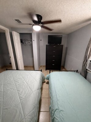 A bedroom with two beds, a ceiling fan, a dresser, and a television. - Entire Home Centrally Located Near Bel Air unit 3 (El Paso)