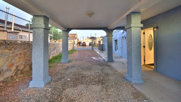 Un paseo techado con paredes y columnas de piedra que conduce a la entrada de un edificio.