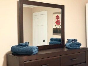 A bathroom vanity with a large mirror, two towels, and a framed artwork on the wall. - Newly Renovated Spacious 4BR peaceful downtown Apt (Montclair)