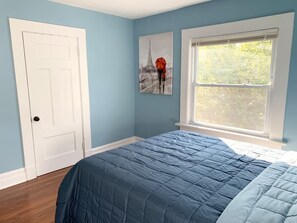 A bedroom with a bed, a window, and a door.
