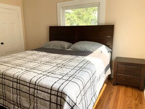 Un dormitorio con cama, mesita de noche y ventana.