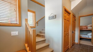 A staircase with wooden steps and a handrail, leading to a bedroom with a bunk bed. - Bear's Paw Chalet - Amazing Location & Ski In/out (Beaverdell)