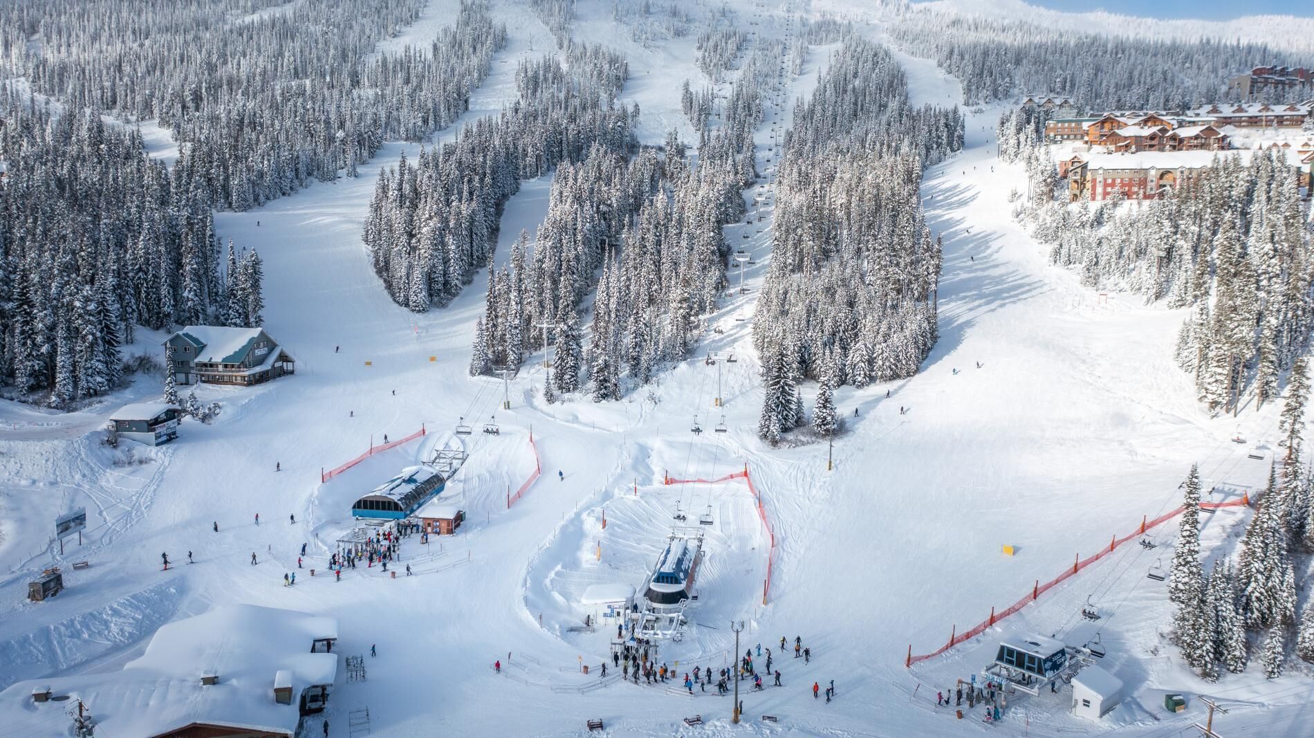 A ski resort with multiple buildings, ski lifts, and a snow-covered landscape.