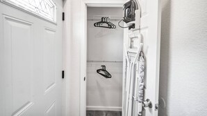 Un couloir étroit avec une porte blanche, un porte-manteau avec des cintres et un rideau de douche.
