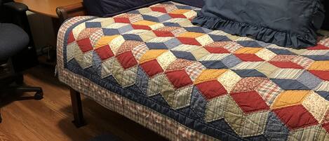 A bedroom with a bed, a desk, a chair, and a rug.