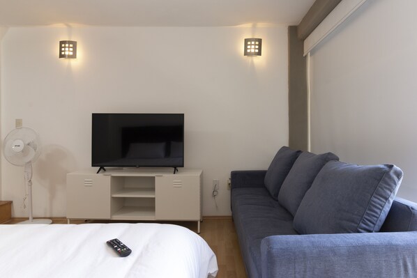 Relax in a spacious room with a large flat-screen TV, comfortable sofa, and a clean, uncluttered layout.