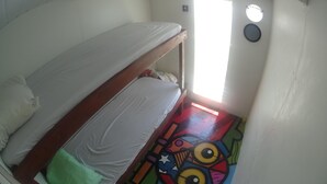 A small, single-bed room with a colorful floor design, a window with a view, and a white wall. - Gorgeous converted fishing vessel in Alter do Chao (Alter do Chao)
