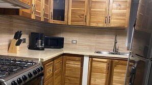 Eine Küche mit Holzausstattung, einem Gasherd, einer Mikrowelle und einem Kühlschrank.
