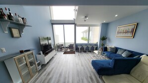 Ein modernes Wohnzimmer mit einem blauen Sofa, einem beigen Sofa, einem Fernseher und einer Glasvitrine.