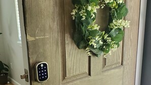 Puiset ovet, joissa on numerokoodilukko, ovenkahva ja koristeellinen seppele.