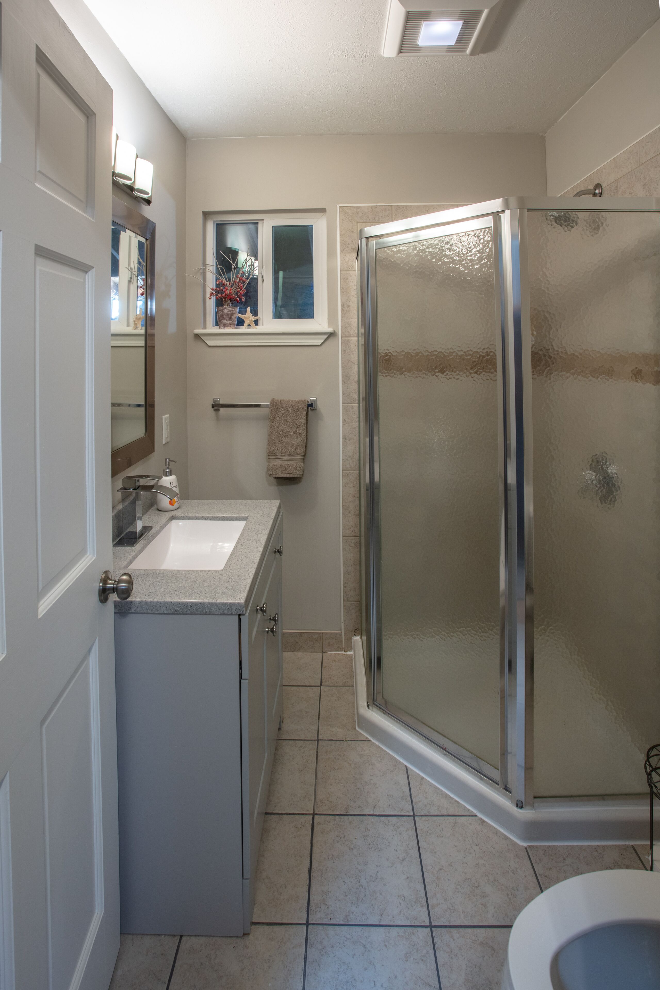 A bathroom with a glass shower enclosure, a sink, and a toilet.