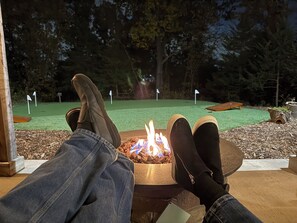 Iemand ontspant met de benen op een tafel, met uitzicht op een minigolfbaan in de nacht.