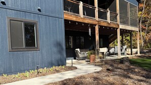 A modern building with a covered patio area, outdoor seating, and a wooden deck. - Two Bedroom Relaxing Woodland Getaway with Putting Green and Walking Trails (Edwardsville)