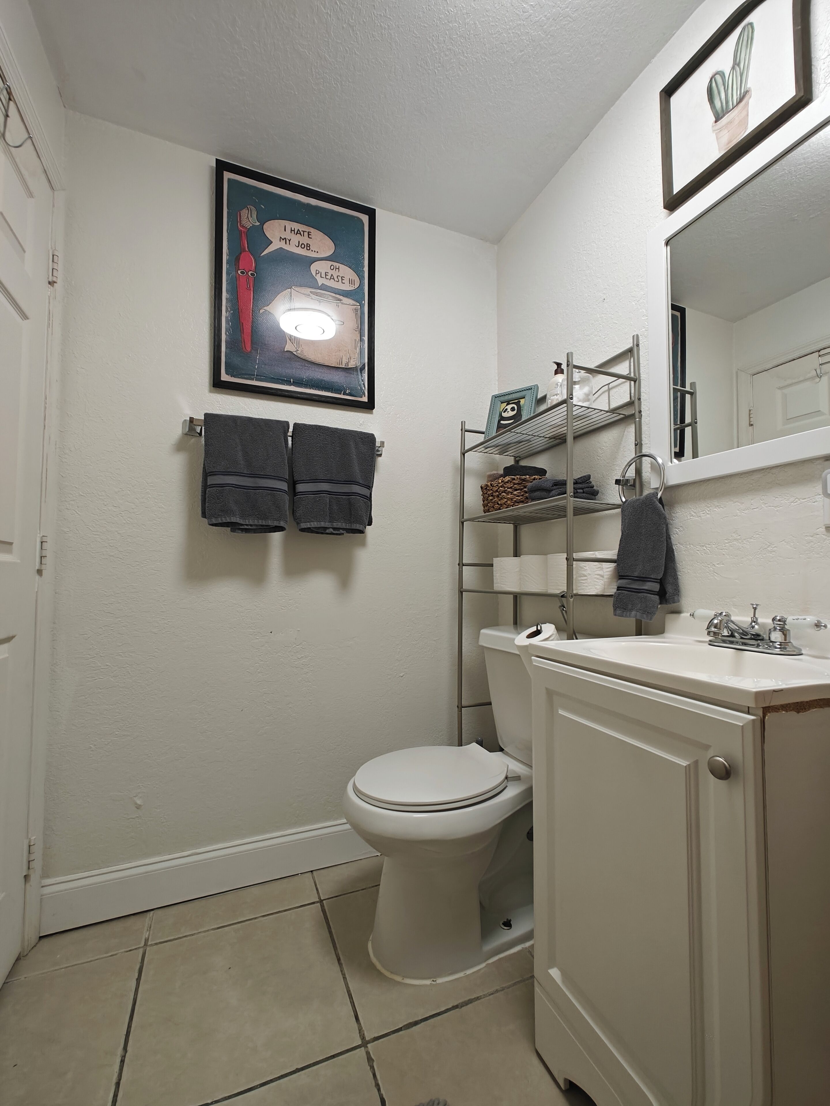 Ein Badezimmer mit Toilette, Waschbecken und Ablagefläche für Toilettenartikel. Zwei Handtücher hängen an der Wand.