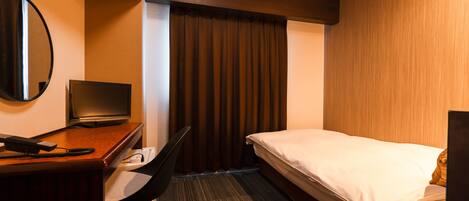 Habitación de hotel con cama, escritorio con computadora, silla, televisor y ventana grande con cortinas.