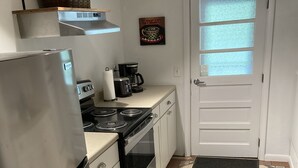 A compact kitchen with a refrigerator, stove, and a coffee maker on the counter. - Visit Monticello, Wineries, UVA:  Room for a Crowd (Troy)