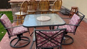 An outdoor patio with a stone table and six chairs, a barbecue grill, and a wooden fence in the background. - 3 bedroom house 5 minutes away from the airport in Colorado Springs all for you. (Colorado Springs)