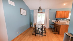 A kitchen with wooden cabinets, a dining table with stools, and a hanging light fixture. - 5 Bedroom Lincoln Home 10 Minutes from Downtown (Lincoln)