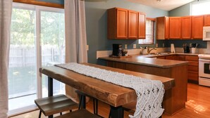 A kitchen with wooden cabinets, a central island, and a dining area with a bench and table. - 5 Bedroom Lincoln Home 10 Minutes from Downtown (Lincoln)