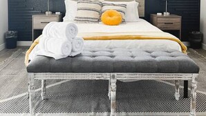 Un dormitorio con cama, mesitas de noche, un banco y una ventana.