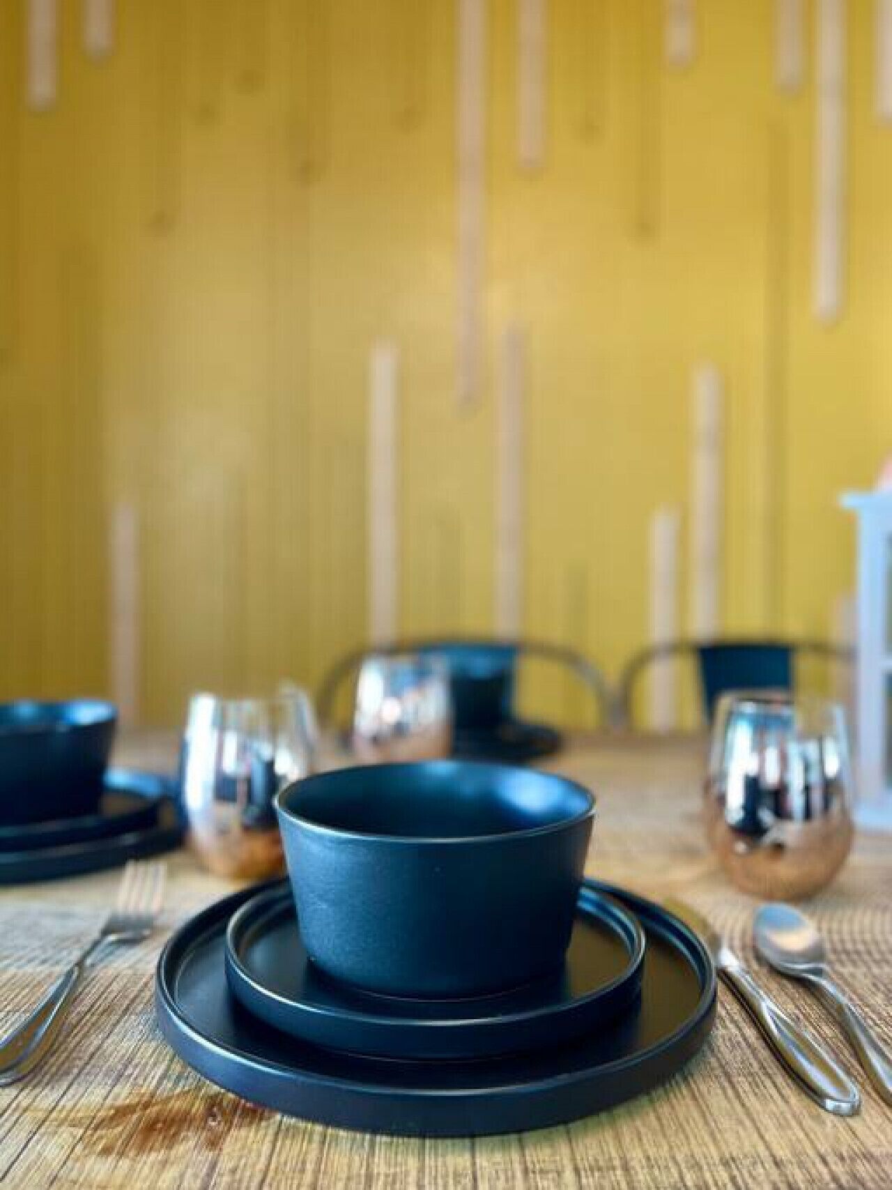 A dining table with a dark blue bowl and plate set on a wooden table.