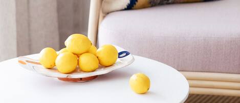 A white round table with a plate of lemons and a single lemon on it, placed on a beige floor.
