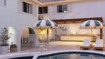 A swimming pool area with lounge chairs and umbrellas, a building with a 'Motel Molly' sign, and a white fence.