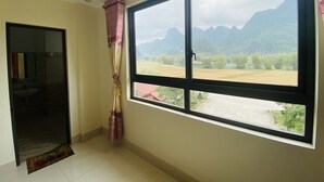 A room with a large window offering a view of mountains and a river. - Khach san So Oanh  (Dam Thuy)