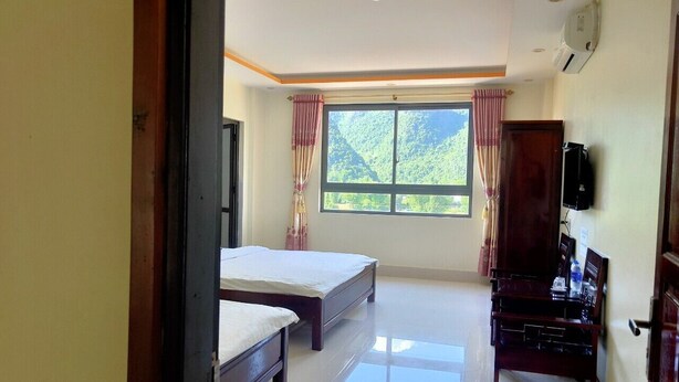 A room with two beds, a desk, and a TV. - Khach san So Oanh  (Dam Thuy)