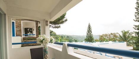 Ein Balkon mit Glastisch, Blumenvase und Blick auf eine Berglandschaft.