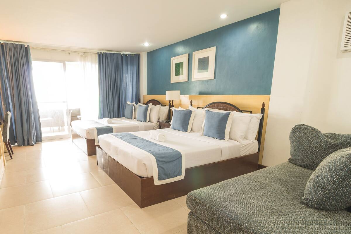 Une chambre d’hôtel avec deux lits, un bureau avec un ordinateur, une chaise et un canapé.