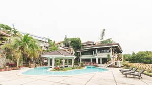 A swimming pool with lounge chairs, a gazebo, and a two-story building with a balcony. - Estancia Resort Hotel (Tagaytay)