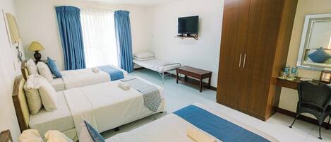 A hotel room with two beds, a desk, a chair, a TV, and a wardrobe.