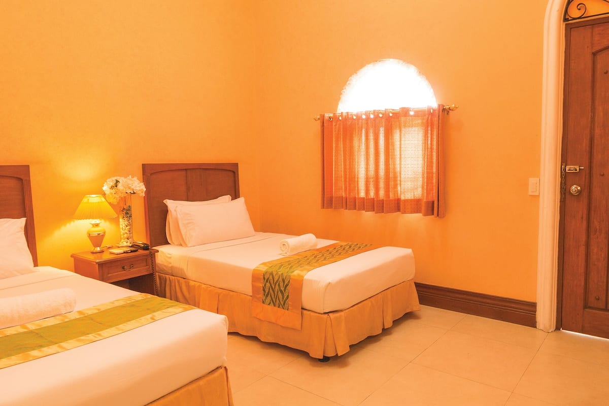 Une chambre d’hôtel avec deux lits, une porte en bois et une lampe sur une table de chevet.