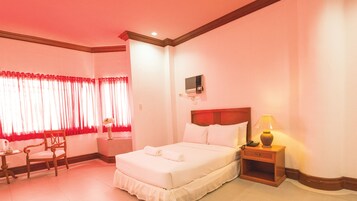 Una habitación de hotel con cama, mesita de noche, lámpara y una silla.