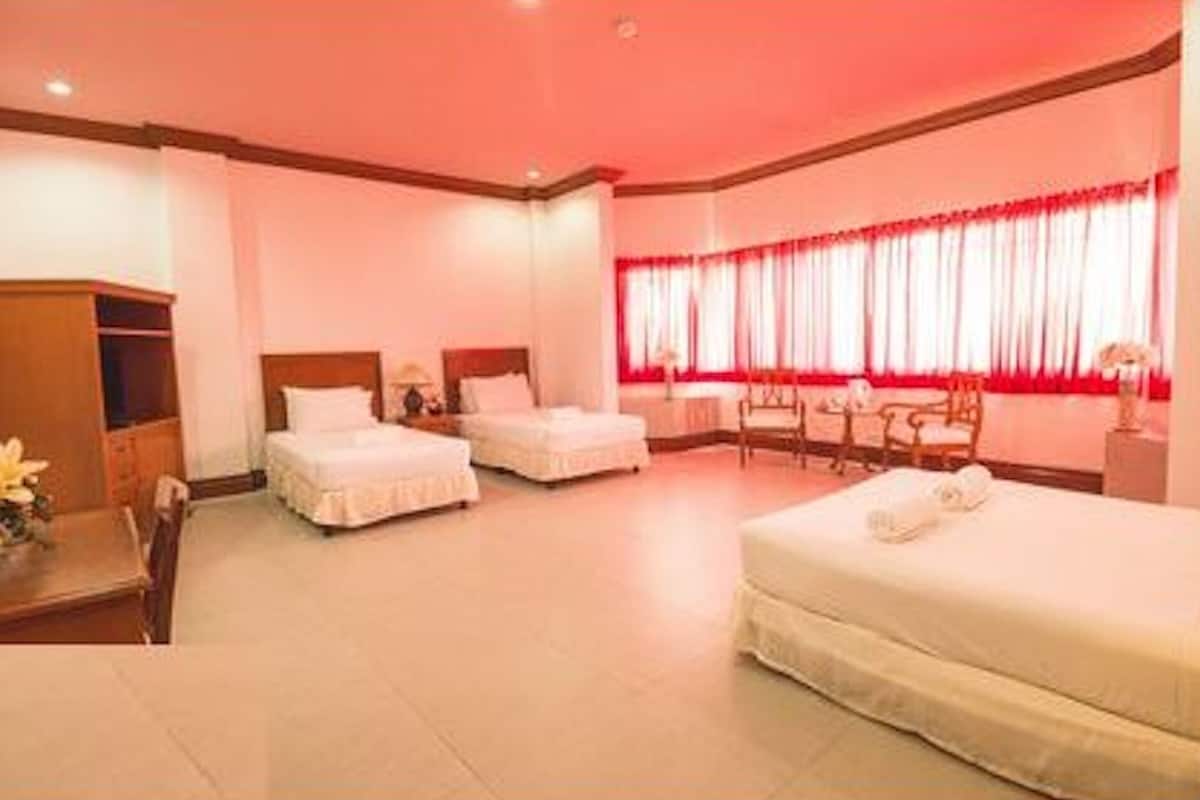Une chambre d’hôtel avec deux lits simples, un grand lit, un bureau et une chaise.