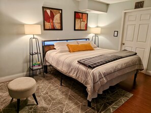 A neatly arranged bedroom with a bed, two wall-mounted lamps, a bookshelf, and a door with a 'No Smoking' sign.