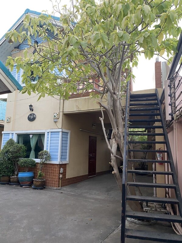 A residential building with a visible number '9' sign, a staircase, and a tree in the foreground.