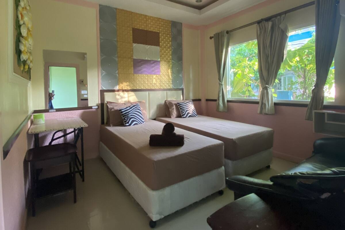 A hotel room with two beds, a desk, and a window with curtains.