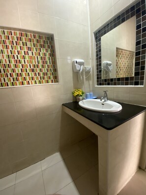 A bathroom with a white sink, black countertop, and a mirror with a black frame. There are two hair dryers mounted on the wall.
