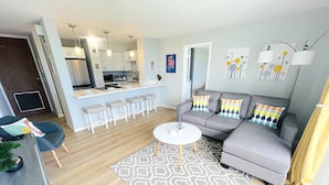 Un salon moderne avec un canapé gris, un tapis à motifs et une petite table basse blanche.