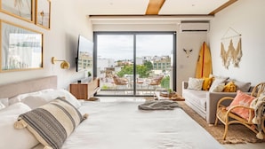 Un dormitorio moderno con una cama grande, un sofá y un balcón con vistas a la ciudad.