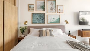 Un dormitorio con cama, cuadros en la pared, televisor y armario de madera.