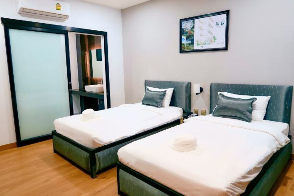 Quarto de hotel com duas camas, um guarda-roupa, um espelho e um mapa emoldurado na parede.