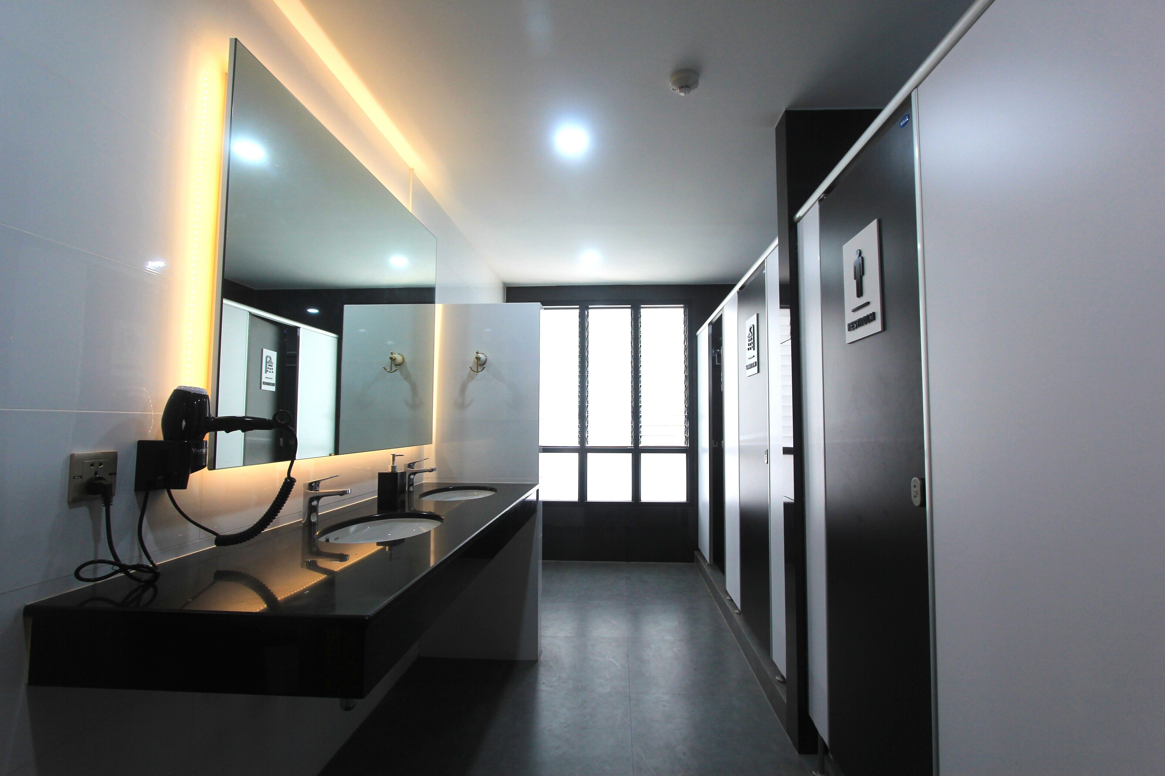 A modern bathroom with two sinks, a large mirror, and a window providing natural light.